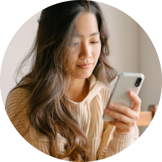 Woman with long hair looks down at mobile phone in her hand