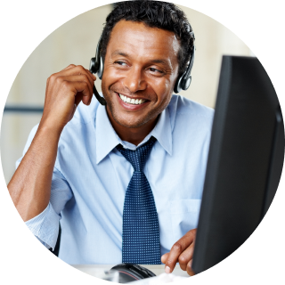 Smiling man adjusts headset and looks to the side with a monitor in the foreground