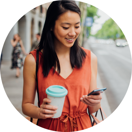 Woman holding coffee cup while looking at her cell phone