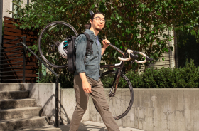 A man carrying his bicycle down some stairs