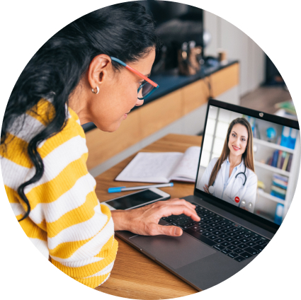 Woman wearing glasses looking at her laptop with a doctor on the screen
