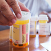 prescriptions bottles with a hand on one of the caps