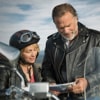 Mature father in motorcycle leathers consults over a map with his daughter in leathers next to her motorcycle