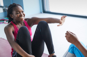 Woman sitting on yoga mat and reaching out to someone