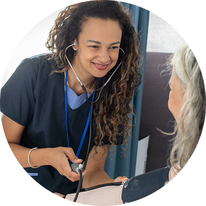 A doctor holds a stethoscope to her patient's arm while measuring their blood pressure.