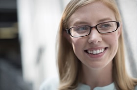 Face of a smiling blonde woman wearing eyeglasses