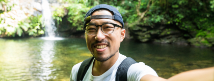 man taking selfie in front of a small waterfall